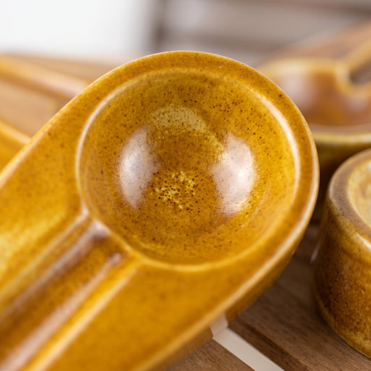 Close-up view of the smooth glaze and unique shape of a vibrant yellow ceramic cigar ashtray.
