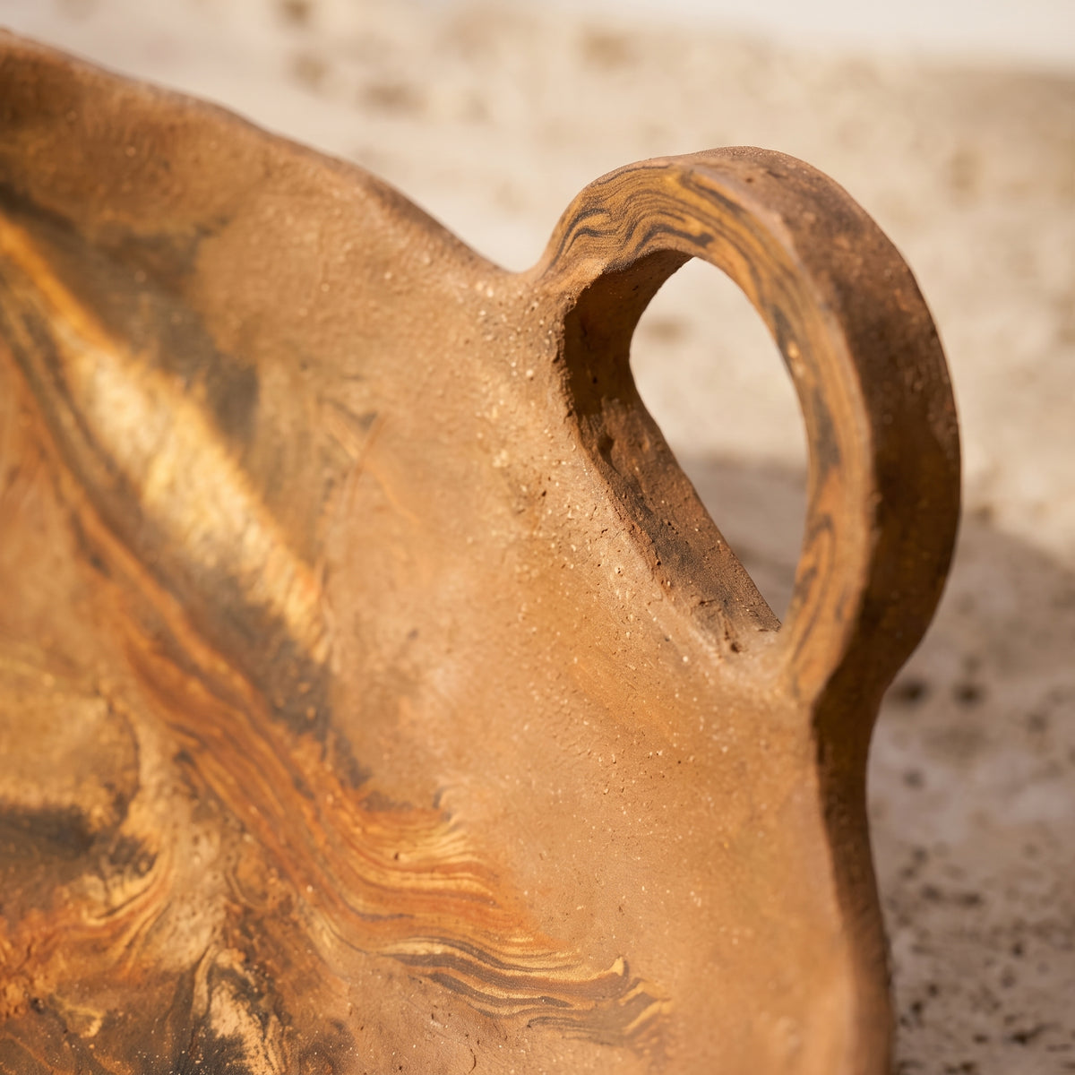 Macro close-up detail focusing on the textured loop handle of the handcrafted ceramic vessel