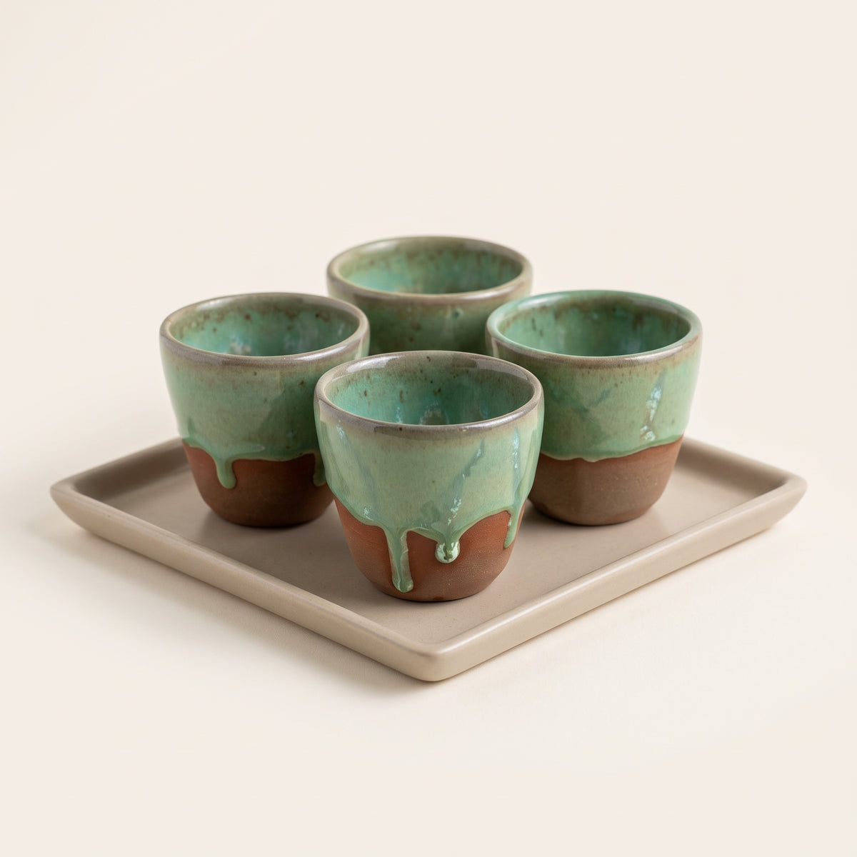 Set of four handmade Olive Sip ceramic cups arranged neatly on a square stoneware serving tray.