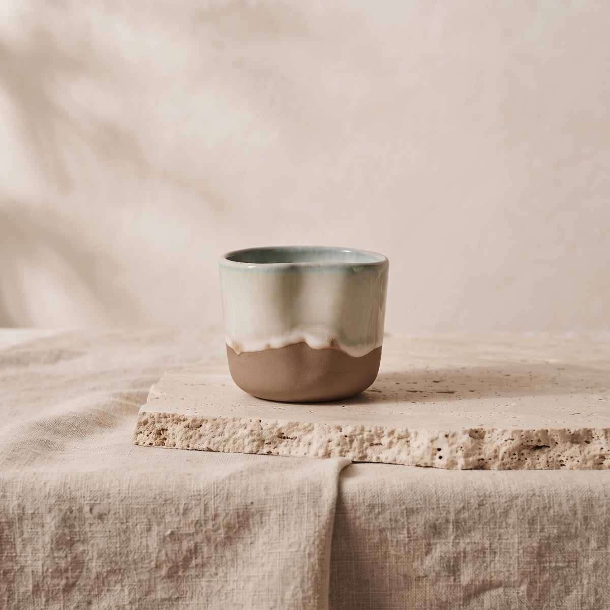 Side profile view of the ceramic cup resting on a neutral stone dining tabletop.