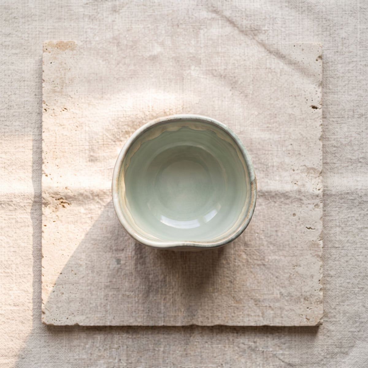 Top-down flat lay view of the handmade ceramic tumbler centered on an earthy linen textile.