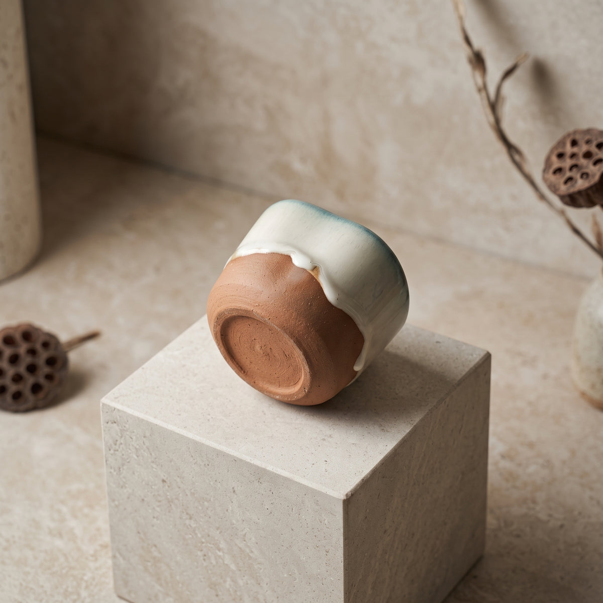 Inverted ceramic tumbler showing the textured unglazed terracotta stoneware bottom and drip glaze.