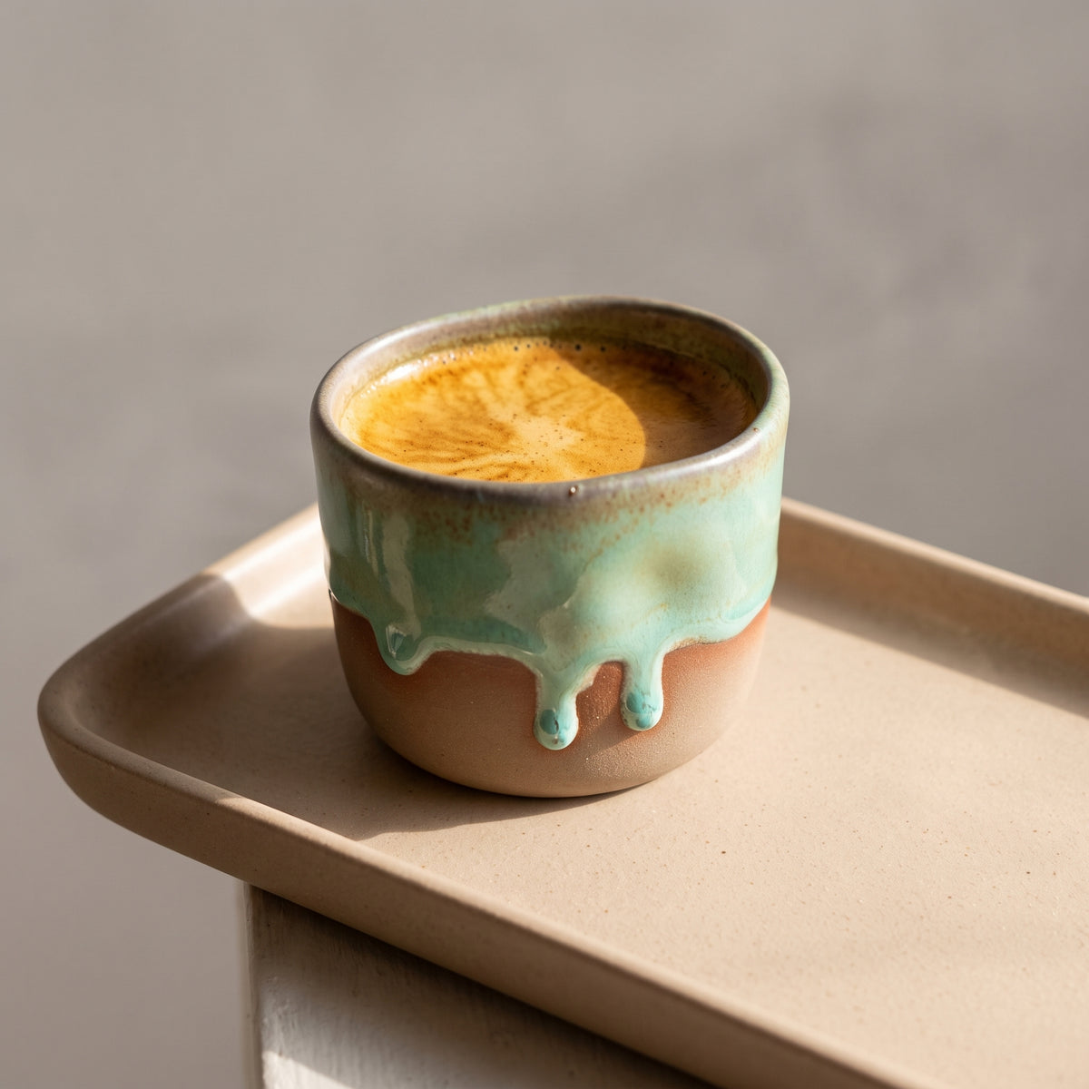 LyLceramics Stone Shot ceramic shot glass filled with golden citrus liqueur on a light wooden tray.