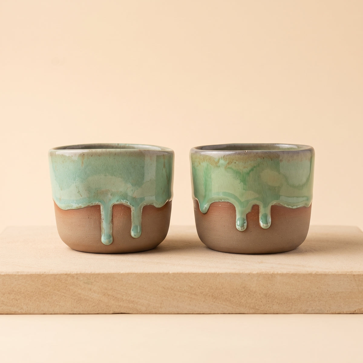Two LyLceramics Stone Shot ceramic shot glasses sitting side by side on an untreated wooden board.