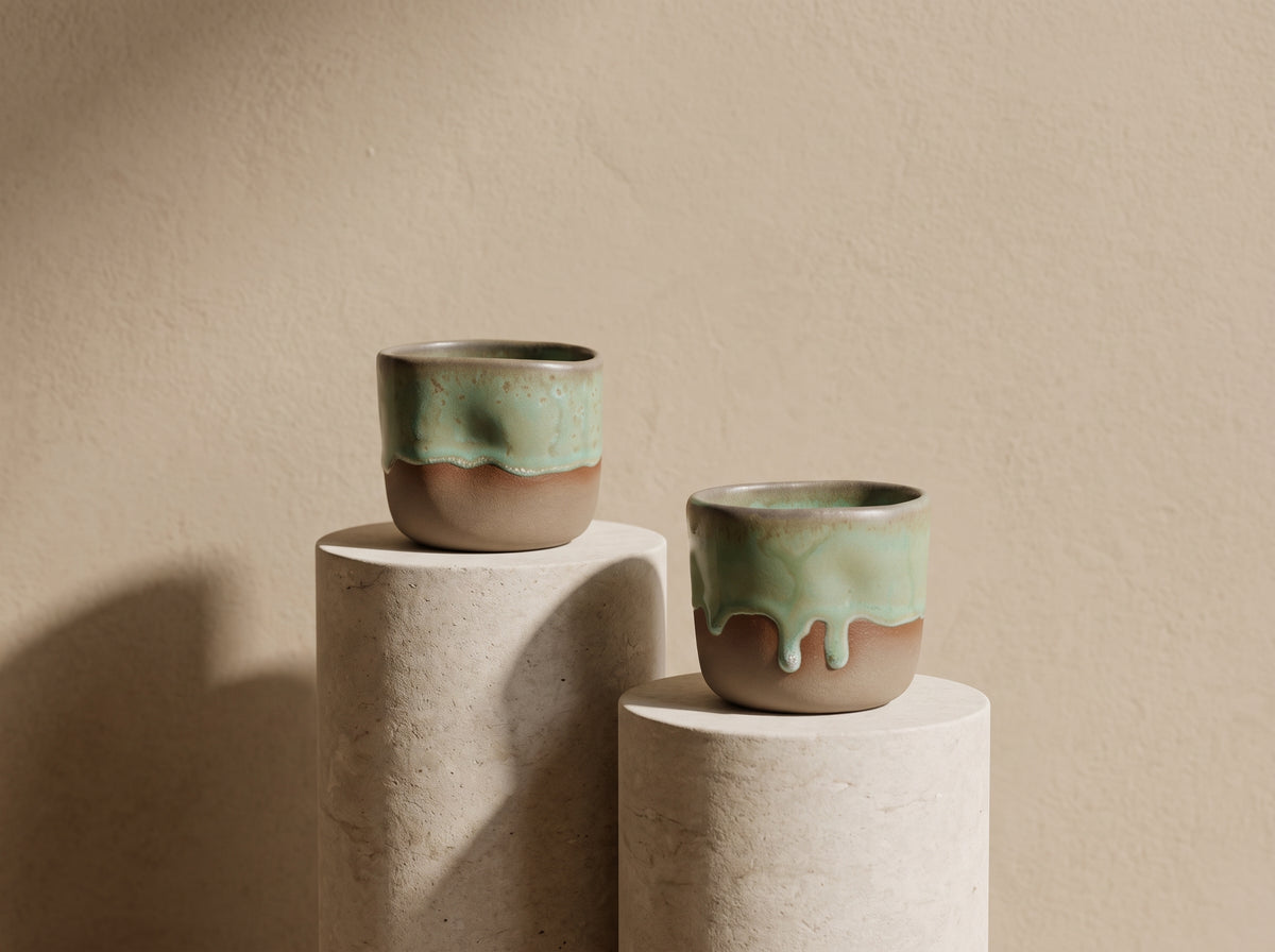 Trio of LyLceramics Stone Shot handmade ceramic shot tumblers arranged on minimalist cylindrical display plinths.