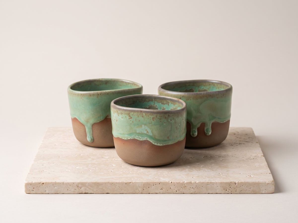 Trio of LyLceramics Stone Shot handmade ceramic shot tumblers arranged on a square stone coaster.