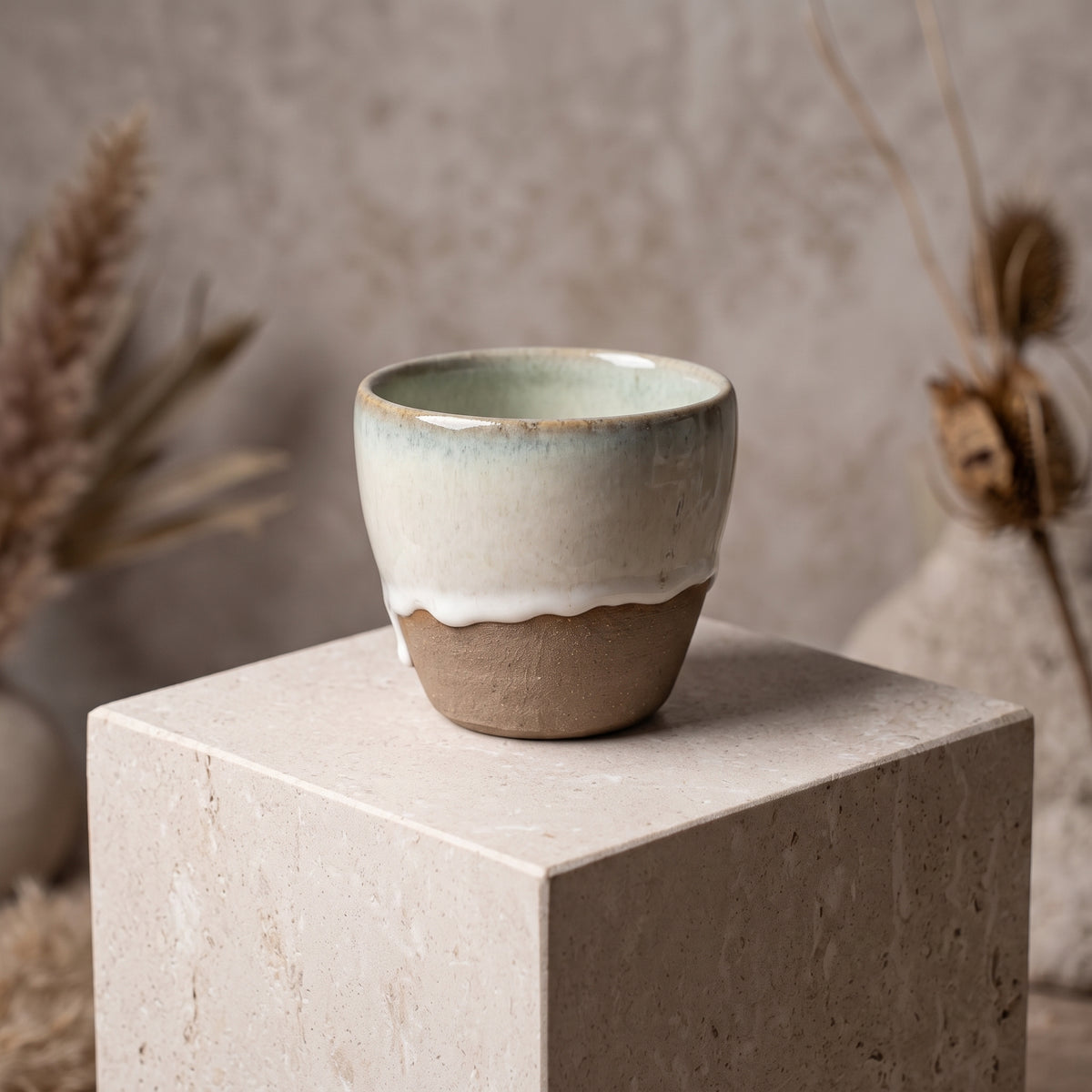 LyLceramics Stone Sip handmade ceramic tumbler displayed on a square concrete plinth.