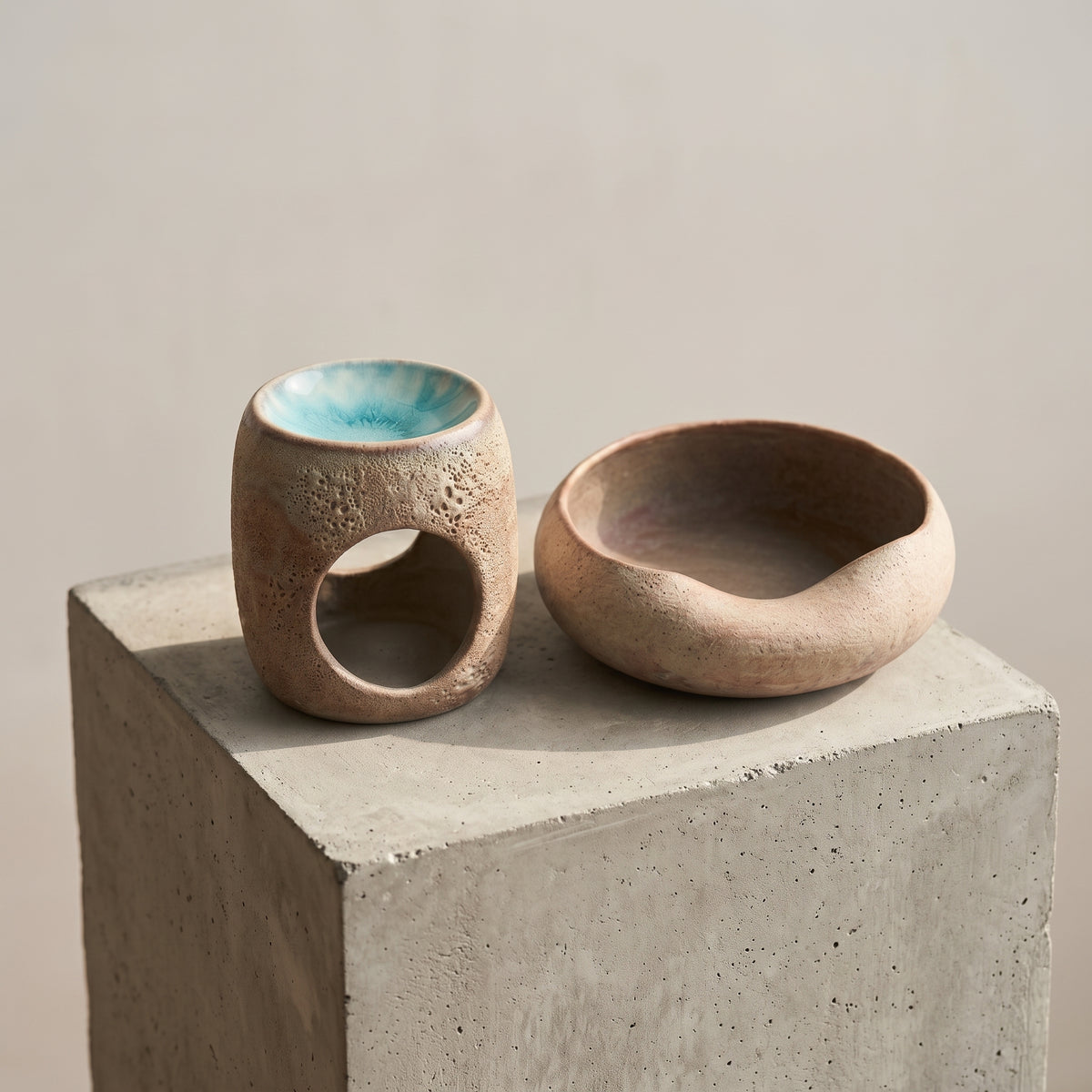 Minimalist ceramic incense holder and bowl set displayed on a grey concrete display pedestal