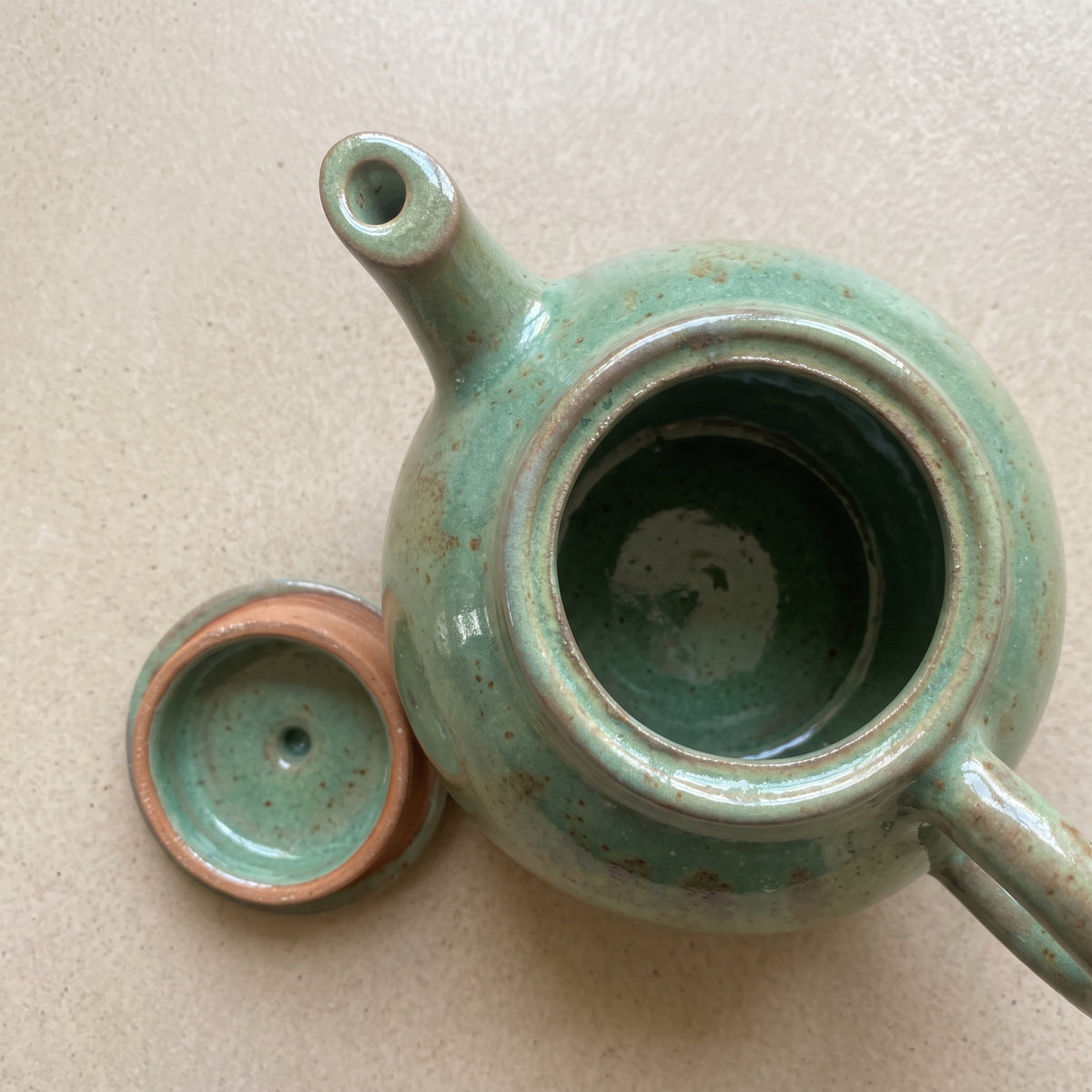 Overhead view into open stoneware teapot displaying interior glazed finish and chamber.