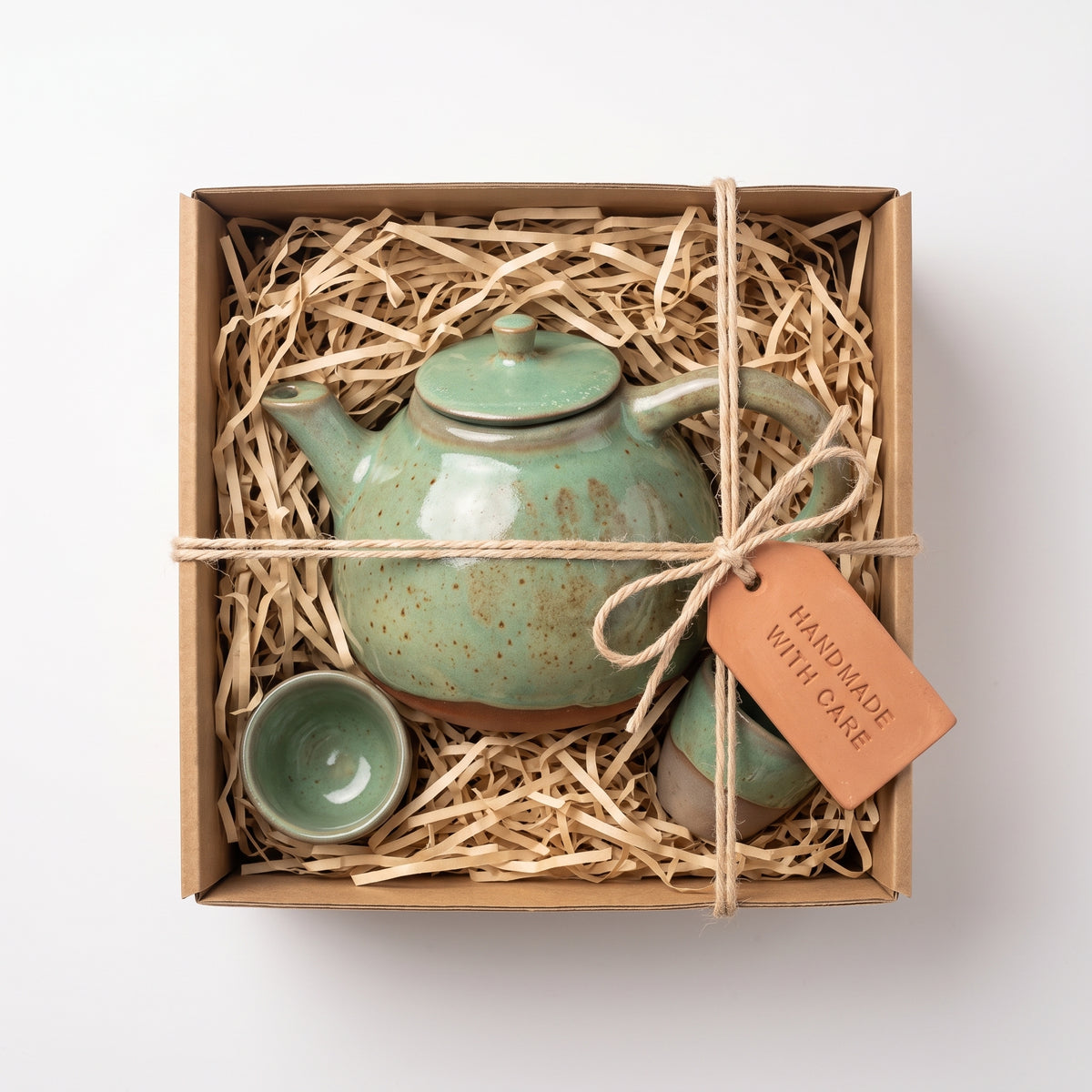 Handmade ceramic tea set packed securely in kraft gift box with shredded paper filler.