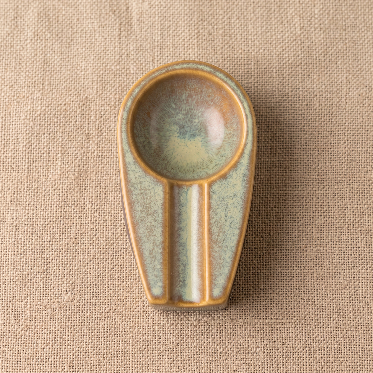 Top-down view of a handmade stoneware cigar ashtray showing its ergonomic cigar holder shape