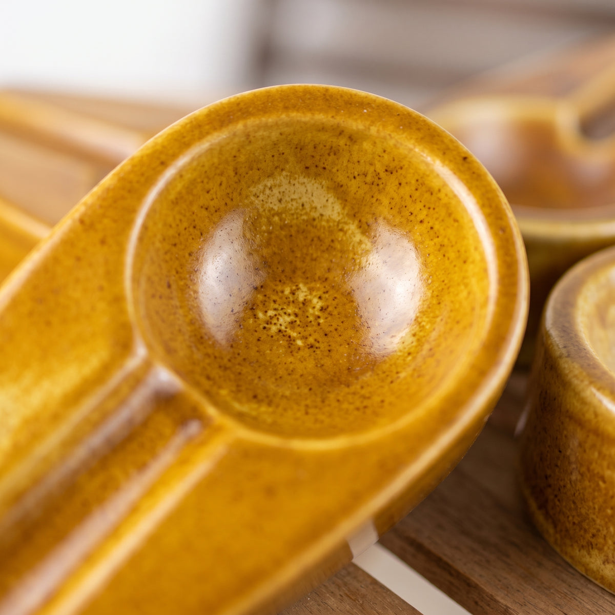 Close-up view of the smooth glaze and unique shape of a vibrant yellow ceramic cigar ashtray.